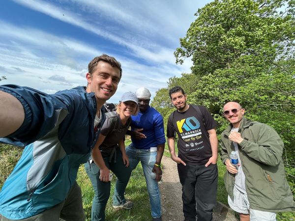 A selfie of five walkers in casual clothes with a blue sky with white clouds in background